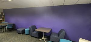 Large Purple wall with chairs and tables in front of it