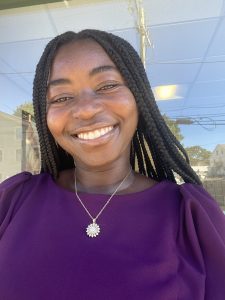 A woman with braids smiling at the camera